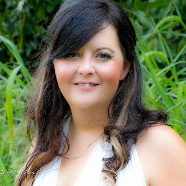 Angela Meer, smiling, outdoors among green leaves